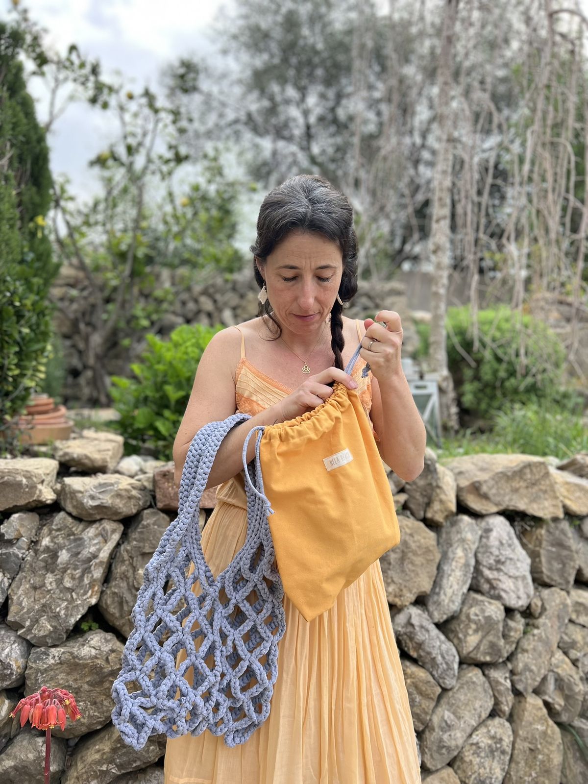 Mujer con bolso Roudera de crochet en la playa, tejido con punto grande y bolsa interior para mayor comodidad y estilo boho-chic.
